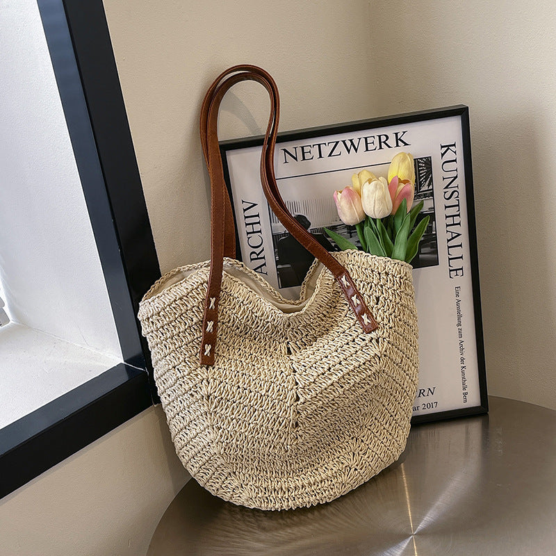 Woven handbag with brown handle on a surface next to a framed newspaper.