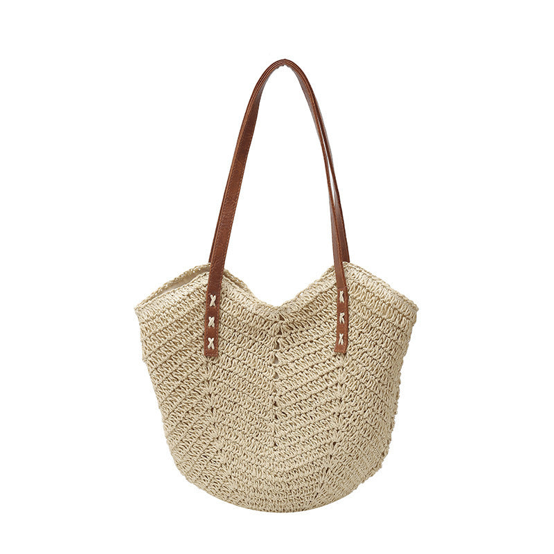 Beige woven handbag with brown leather straps on a white background