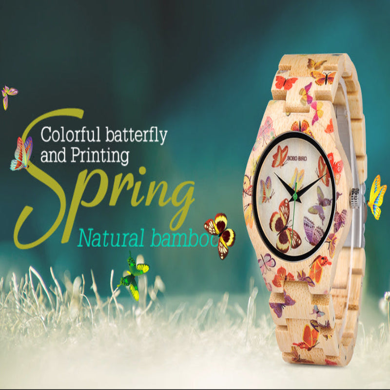 A wristwatch with a natural bamboo strap and a white dial decorated with colorful butterfly prints, shown next to promotional text reading 'Colorful butterfly and Printing Spring Natural bamboo' on a soft green and white background.