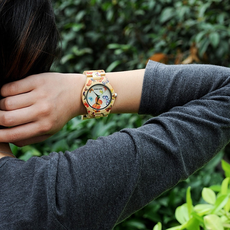 Person wearing a colorful watch with a floral design on a blurred green background