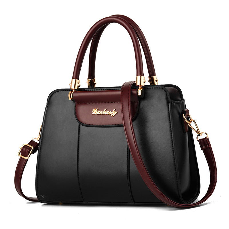 Black handbag with brown handles and strap on a white background