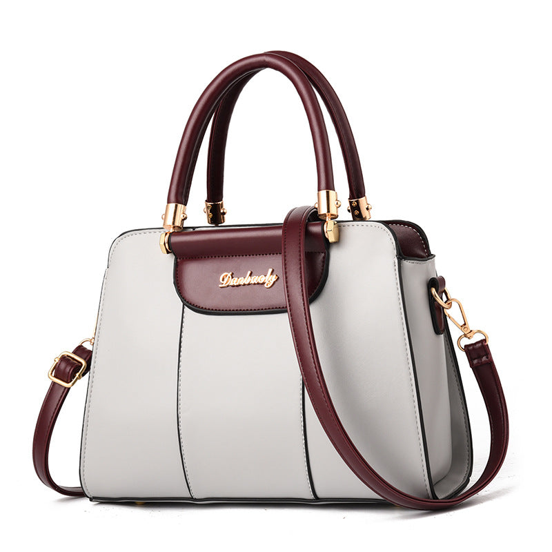 White handbag with brown accents and gold hardware on a white background