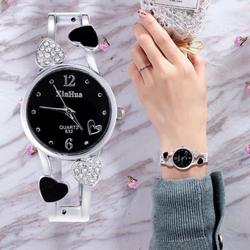 Black watch with heart designs on a marble surface