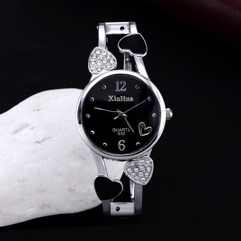 Silver wristwatch with heart designs on a dark background
