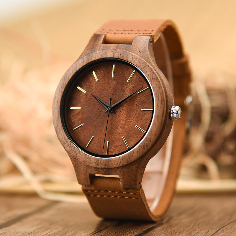 Wooden watch with brown leather strap on a wooden surface