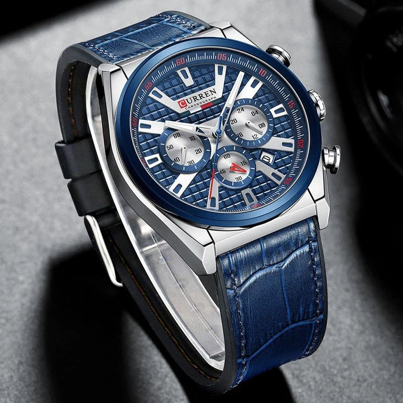 A men's chronograph wristwatch with a blue textured leather strap, a silver-toned stainless steel case, and a blue dial with white and silver subdials.