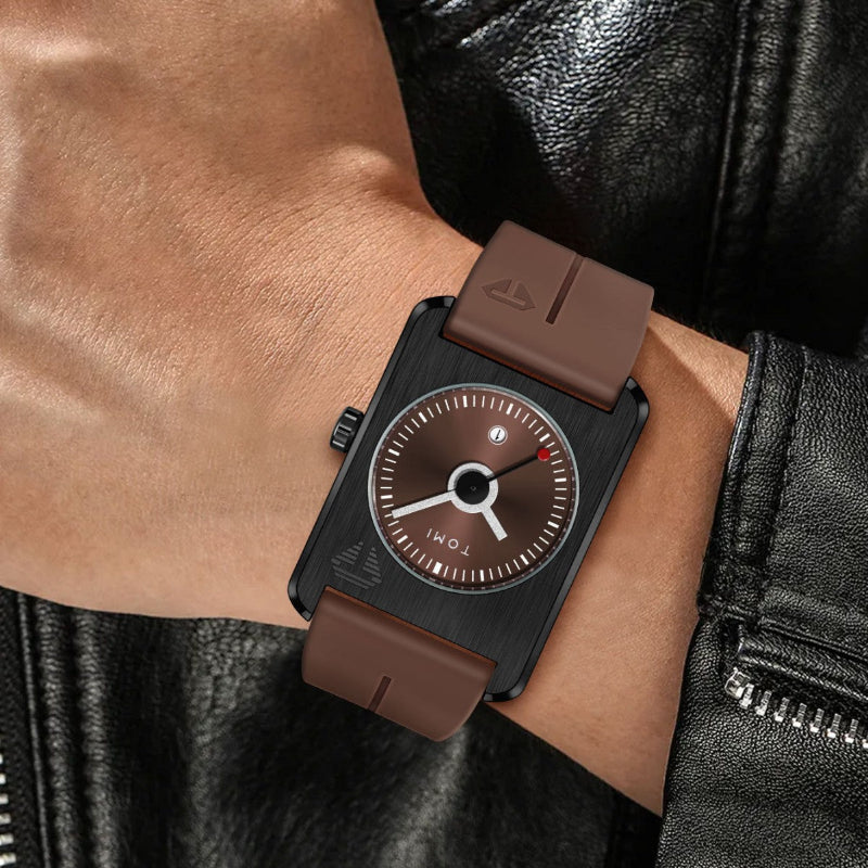 Watch with brown strap and black case on a wrist, wearing a black leather jacket.