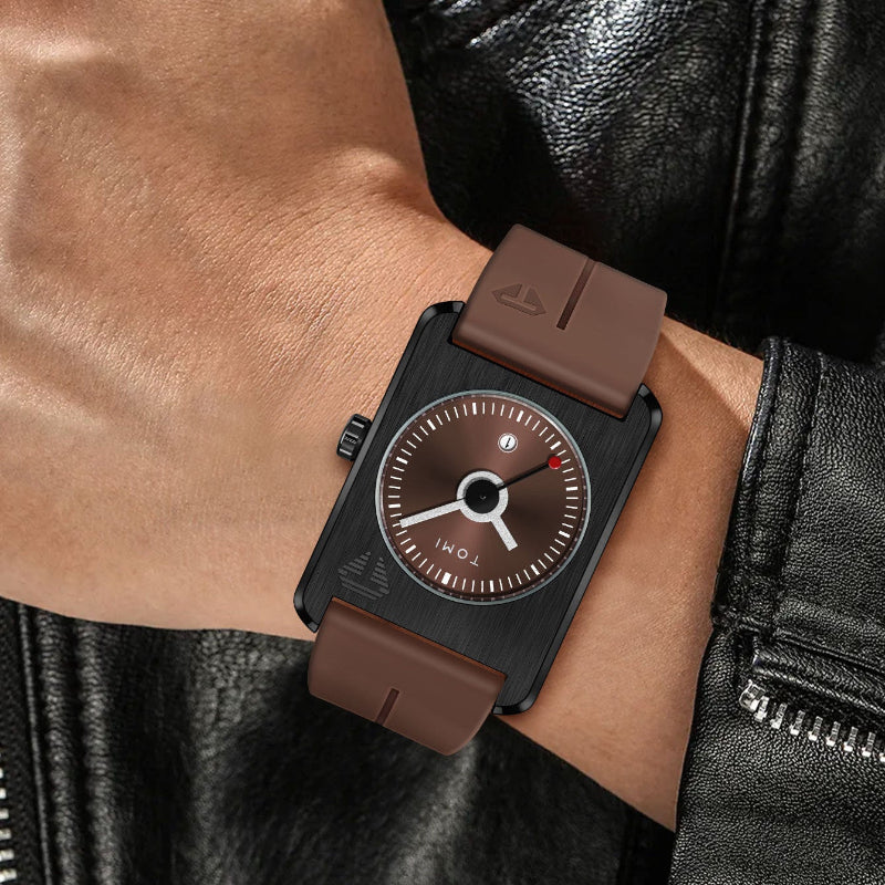 Watch with brown leather strap worn on a wrist, against a black leather jacket background.