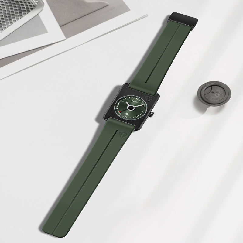 An olive green smartwatch with a matching green strap and a black square case, styled on a white surface with a small round accessory nearby.