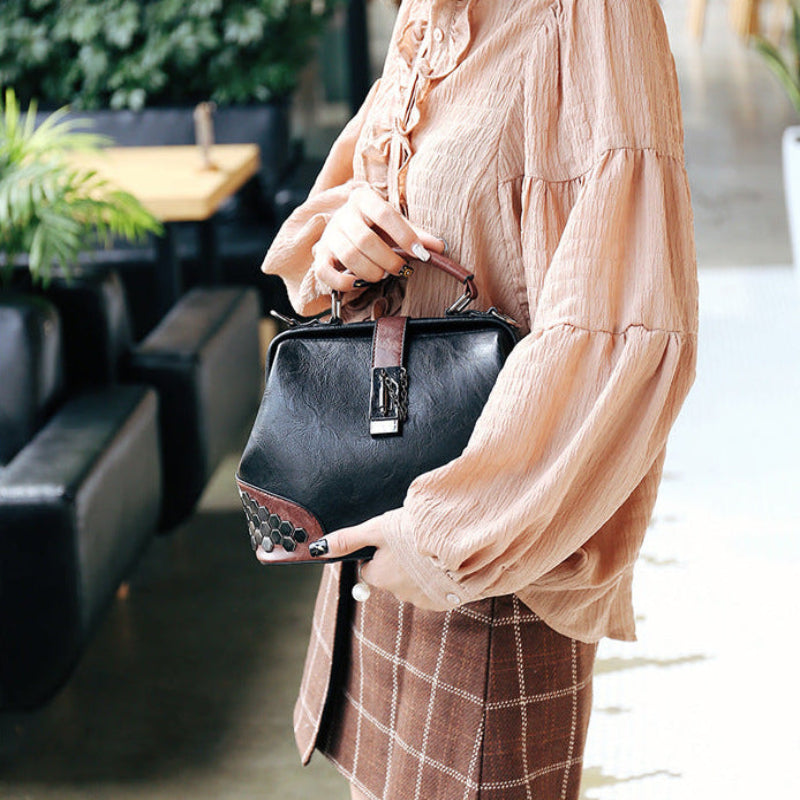 Person holding a black handbag outdoors
