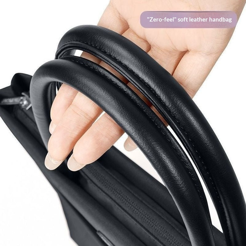 A close-up of a hand holding the padded black leather handle of a handbag, with a text overlay that reads '"Zero-feel" soft leather handbag'.